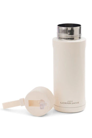 The Lorna Jane Essential Insulated Water Bottle, in cream with a detachable flip straw lid, sits on a white surface. The brand name is visible on the side.