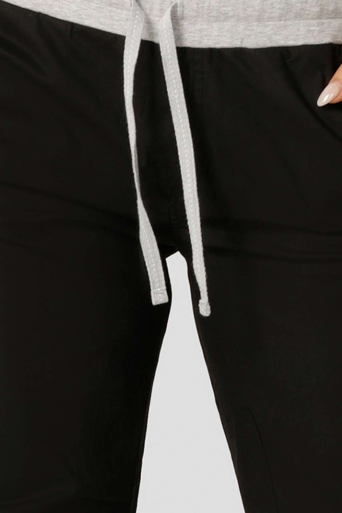 Close-up of a person wearing the Lorna Jane Flashdance Pant, featuring black fabric and an adjustable elastic waist. The lower torso and upper legs are shown, emphasizing the pant's comfort and style.
