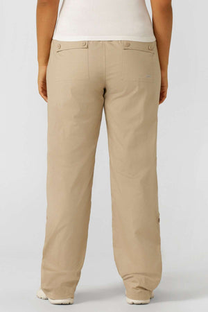 Someone wearing Lorna Jane Flashdance Pant in beige, featuring multiple pockets and back pockets with button flaps, stands with their back to the camera. They pair the pants with a white top against a plain light background.
