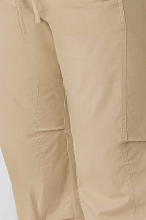 Close-up of light tan Lorna Jane Flashdance Pant with visible seams, side pocket, smooth fabric, relaxed fit, and a partially visible drawstring at the waistband.