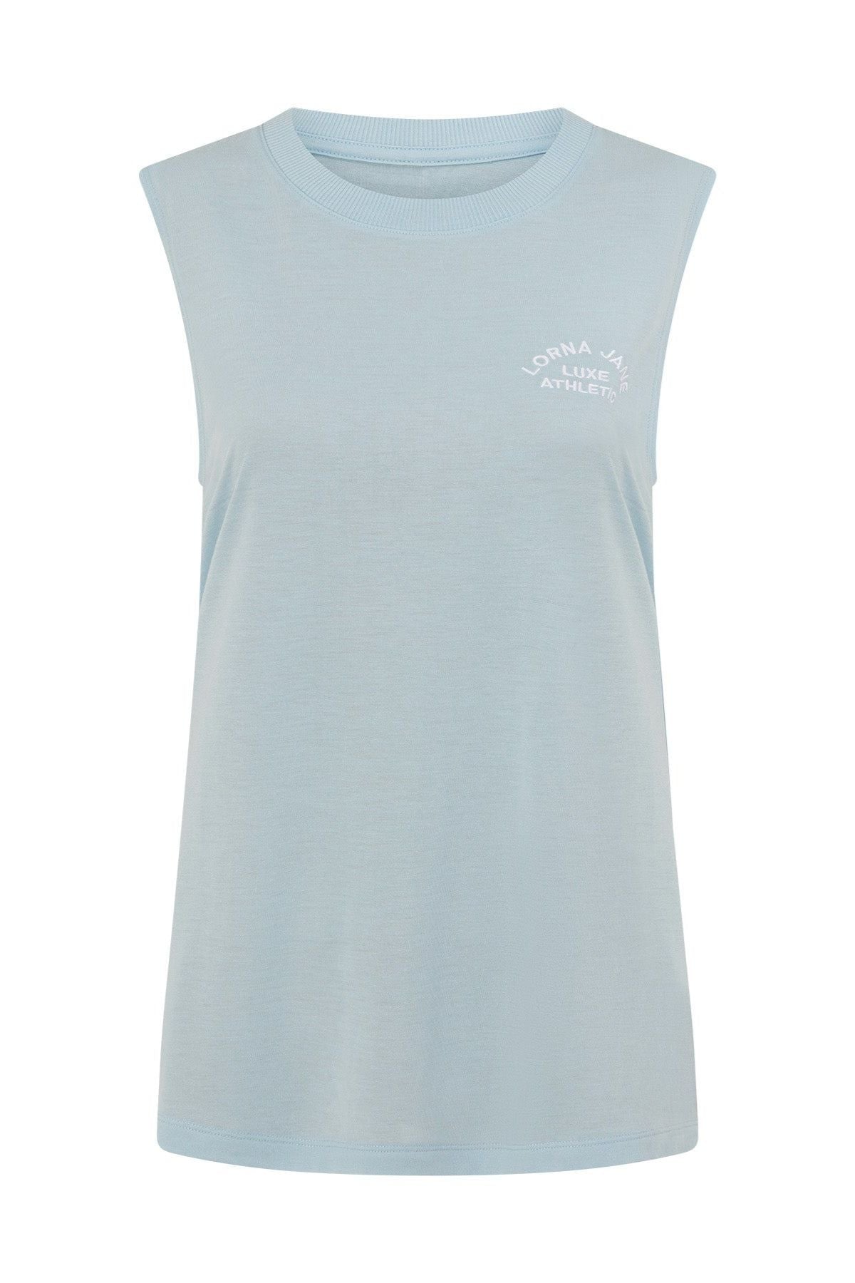 The Lorna Jane Lotus Muscle Tank in light blue features a sleeveless, crew neck design with small white “Lorna Jane Classic Athletic” text on the upper left chest. Made from a soft, slightly stretchy fabric for lightweight layering and breathability, it’s perfect for comfortable workouts or casual wear. The tank is displayed against a plain white background.