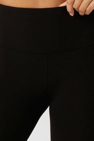Close-up of a person wearing Lorna Jane Lotus No Chafe Ankle Biter Leggings, designed with high-rise fit, 4-way stretch fabric, and a smooth, seamless finish; one hand rests near the waistband.