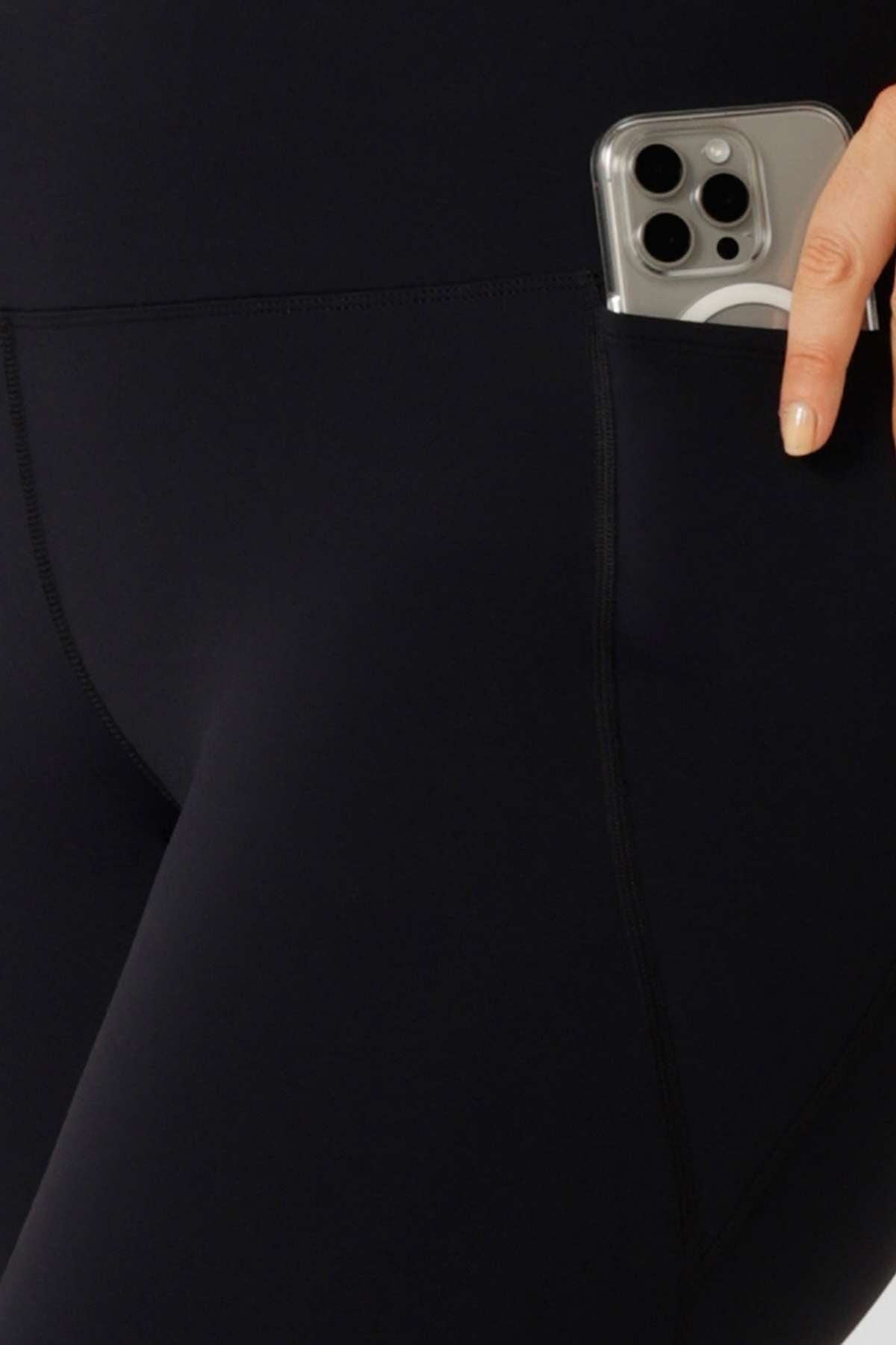 A close-up of a person wearing Lorna Jane Lotus Thermal No Chafe Full Length Leggings, slipping a smartphone into the side pocket.