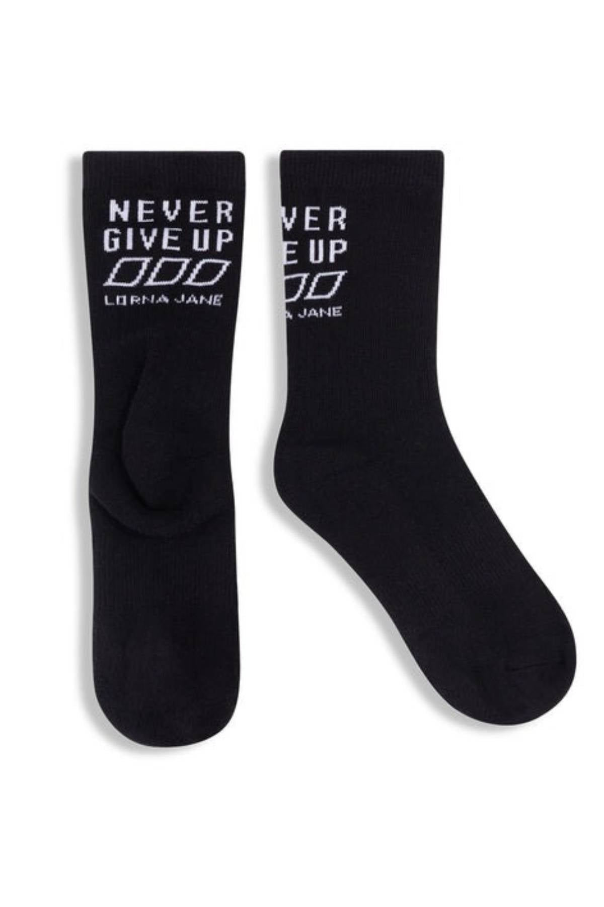Lorna Jane Never Give Up Arch Support Crew Socks are black crew socks with cushioned soles, “NEVER GIVE UP” and “LORNA JANE” in white on the cuffs, and a triple-O logo underfoot.
