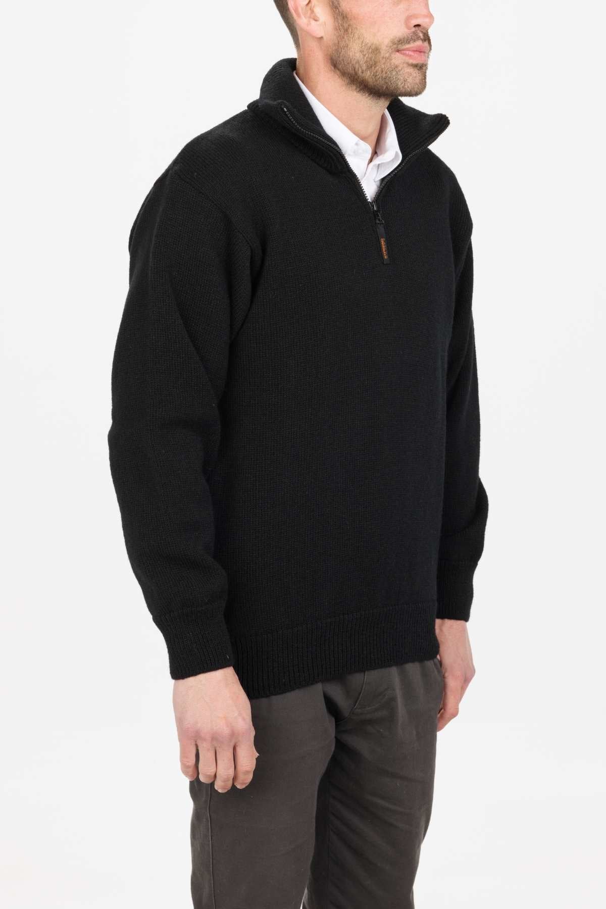 Man in a black MKM North Wester Knitted Jumper, made of 100% wool, and gray pants against a white background. Carefully crafted in New Zealand.