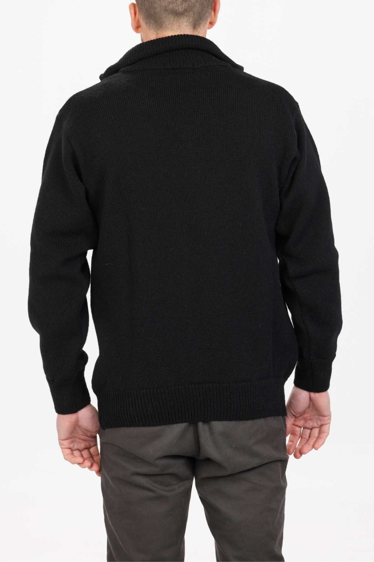 A person is wearing an MKM North Wester Knitted Jumper, color black, made in New Zealand with long sleeves, paired with charcoal pants. They are viewed from the back against a plain white background.