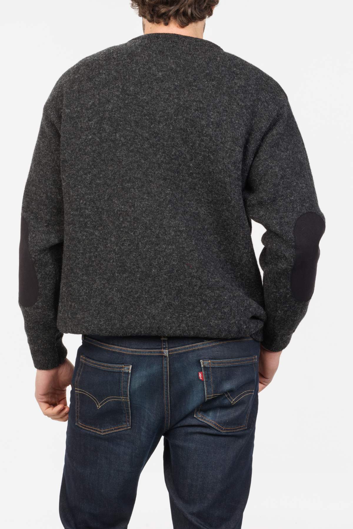 A person is shown from the back wearing a dark gray MKM Tasman Dual Layer Possum & Merino Crew sweater with black elbow patches and blue jeans against a plain white background.