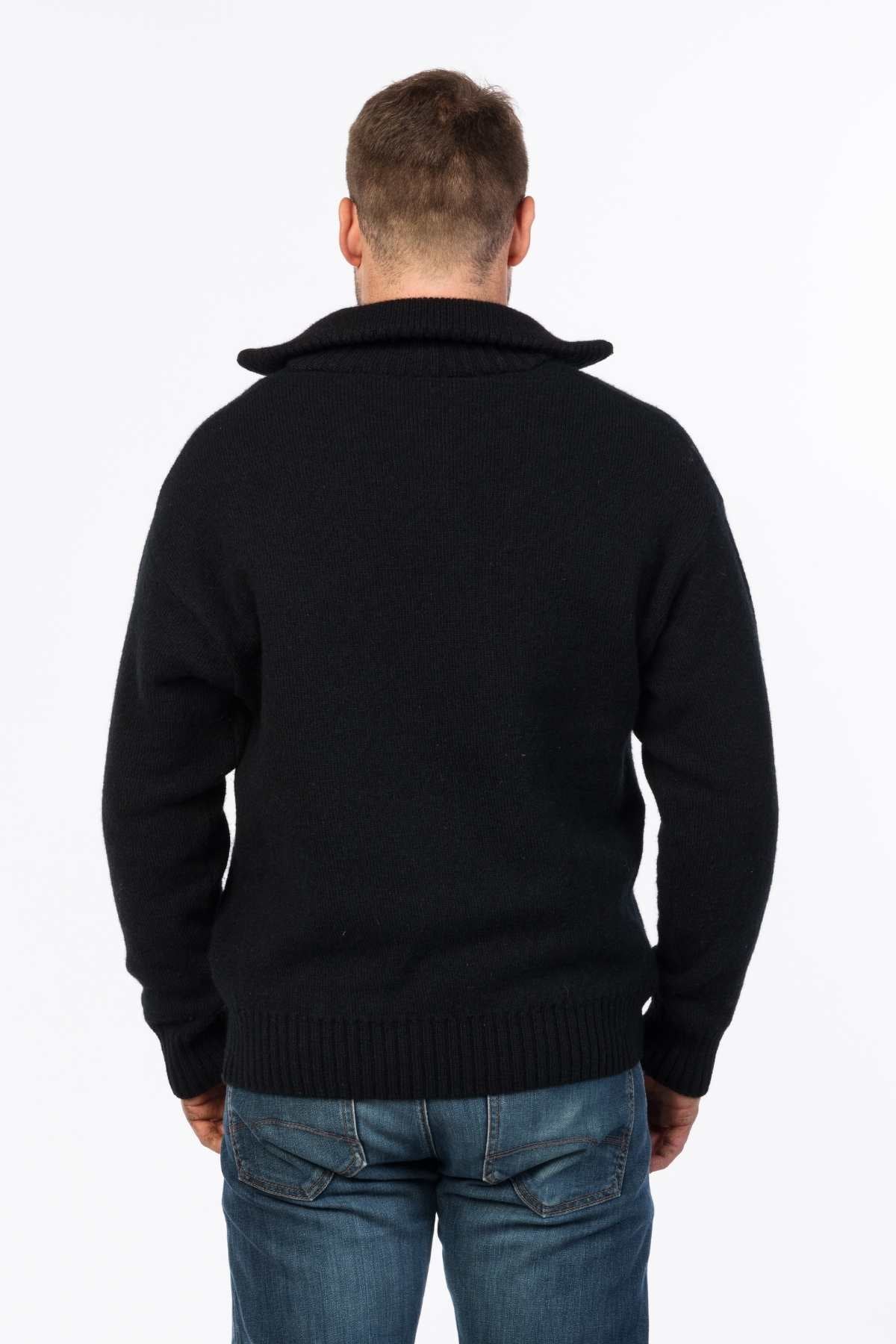 A man stands facing away, wearing a black MKM Tasman Dual Layer Possum & Merino Knit sweater with a folded collar and blue faded jeans. The background is plain white.