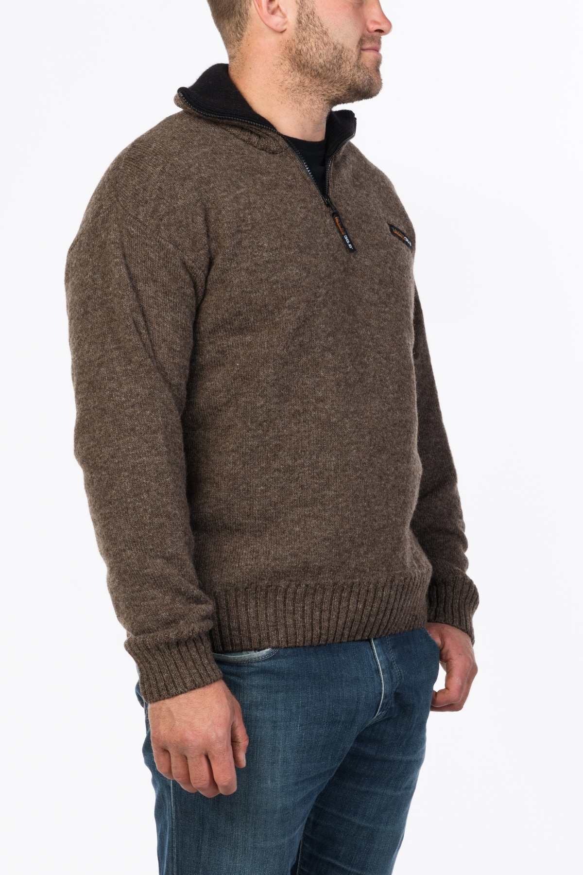 A man stands sideways against a white background, wearing the MKM Tasman Dual Layer Possum & Merino Knit sweater with a ribbed collar and cuffs, paired with blue jeans for a casually refined style.