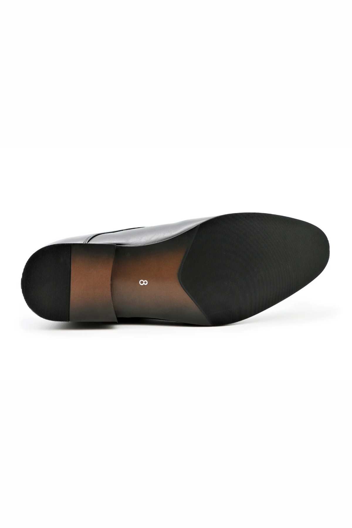 The underside of a black Messa Pisa Shoe is depicted, showcasing a smooth, dark surface with subtly textured areas at the heel and ball. A small, silver infinity symbol is positioned near the center of the sole. The heel area features a gradient brown design and offers customizable support for environmentally conscious wearers.