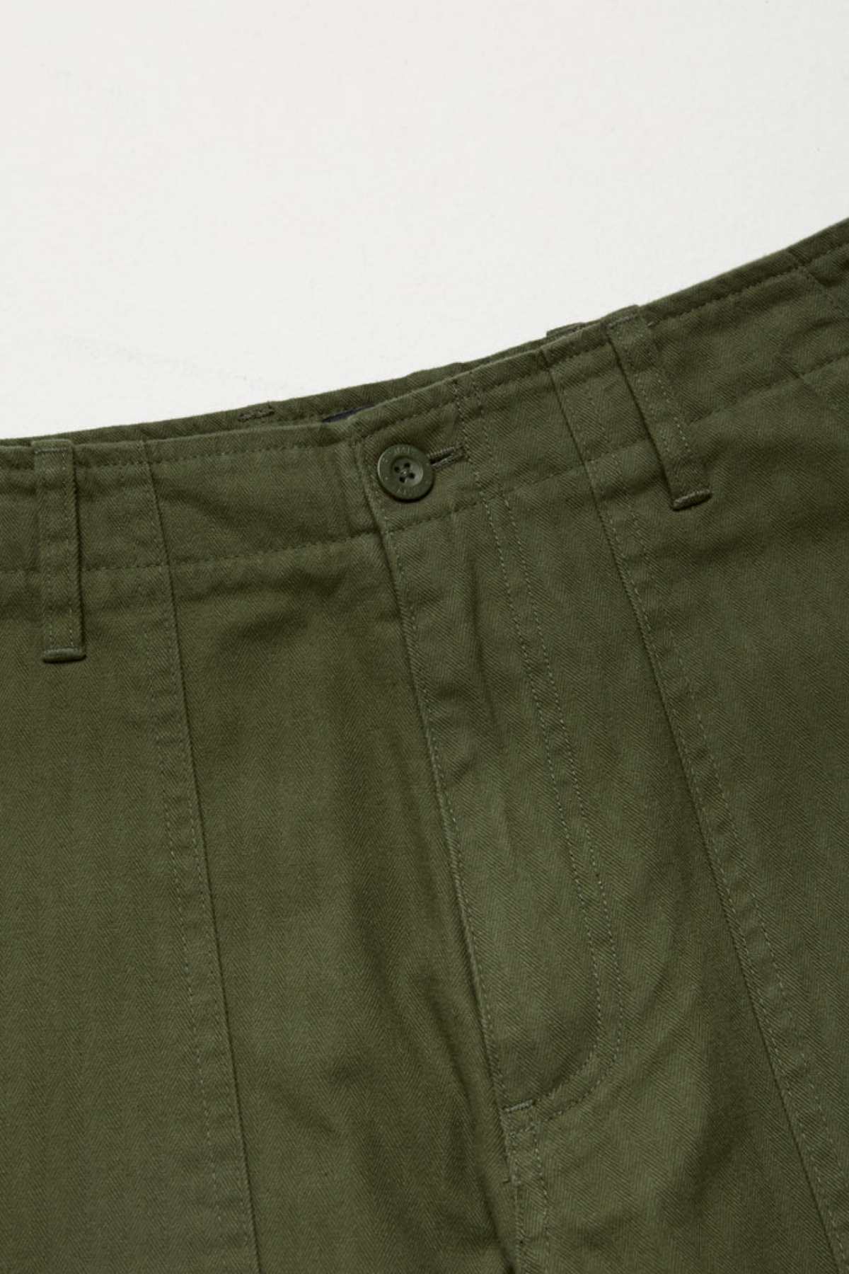 Close-up of the waistband and upper section of the Mr Simple Carpenter Pant in olive green, showing a button closure, belt loops, stitching details, and a workwear-inspired look crafted from 100% cotton on a plain background.