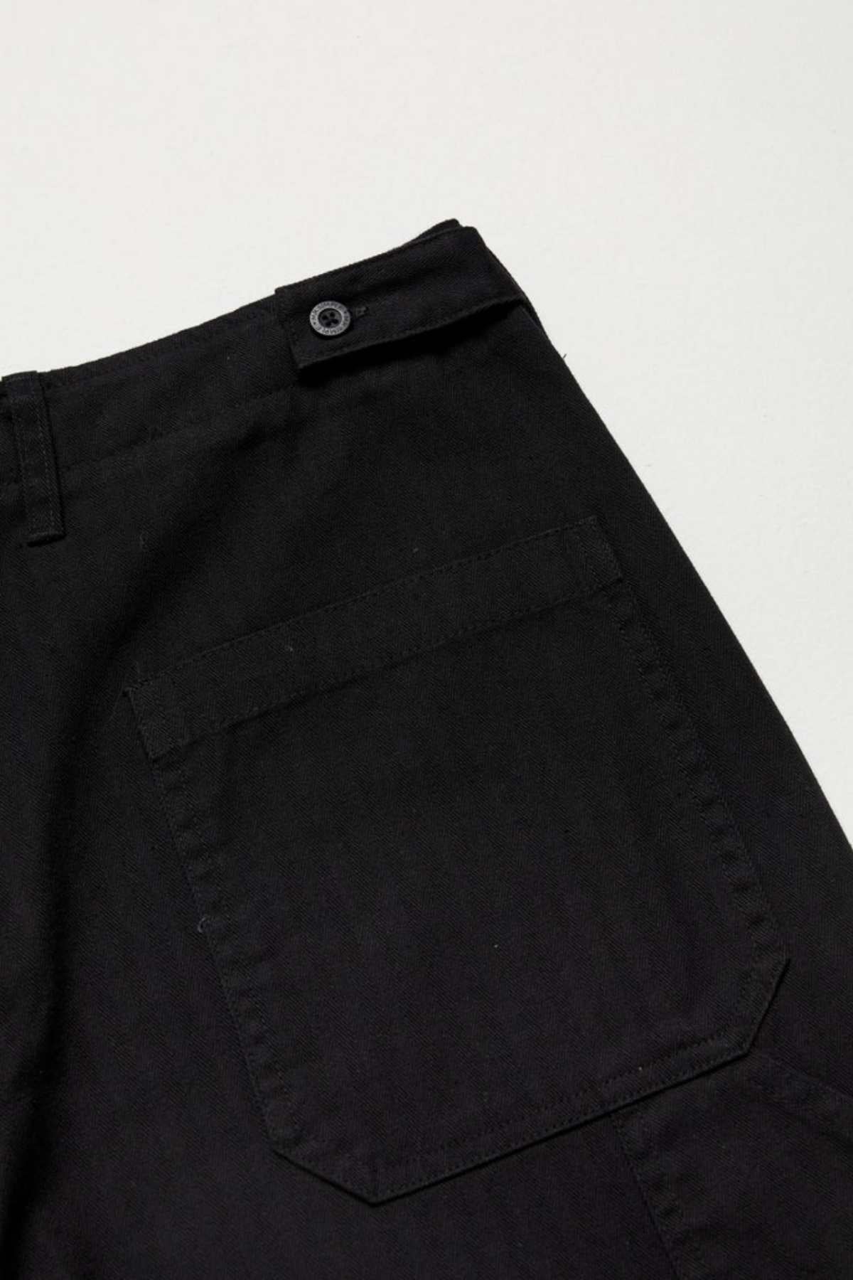 Close-up of Mr Simple Carpenter Pant in black, highlighting a back pocket with a buttoned belt loop above. The workwear-inspired design features smooth fabric and visible stitching along seams and pocket edges, adding rugged charm.