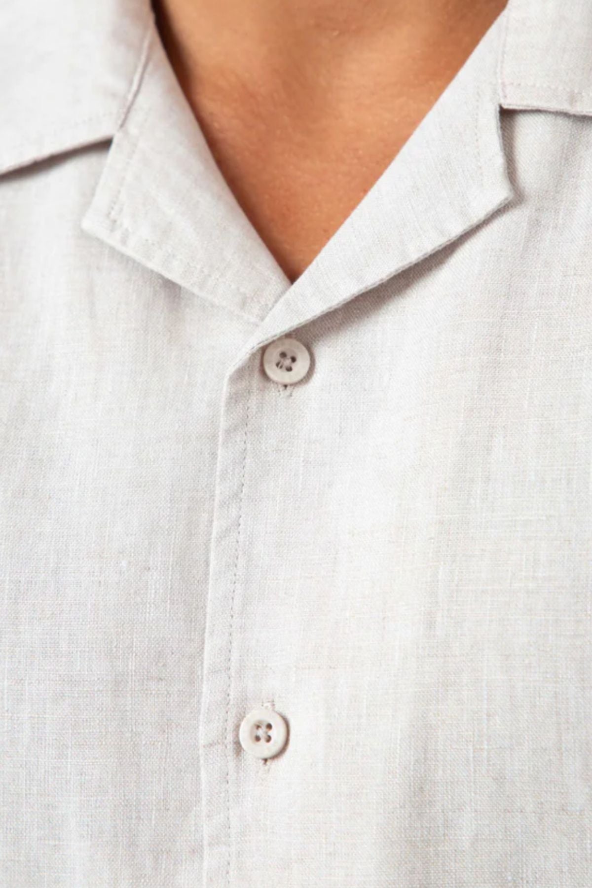 Close-up of the Mr Simple Cuban Short Sleeve Shirt in light beige, showing its relaxed fit, collar, two visible buttons, and lightly textured linen fabric. Only the lower neckline and upper chest are visible.
