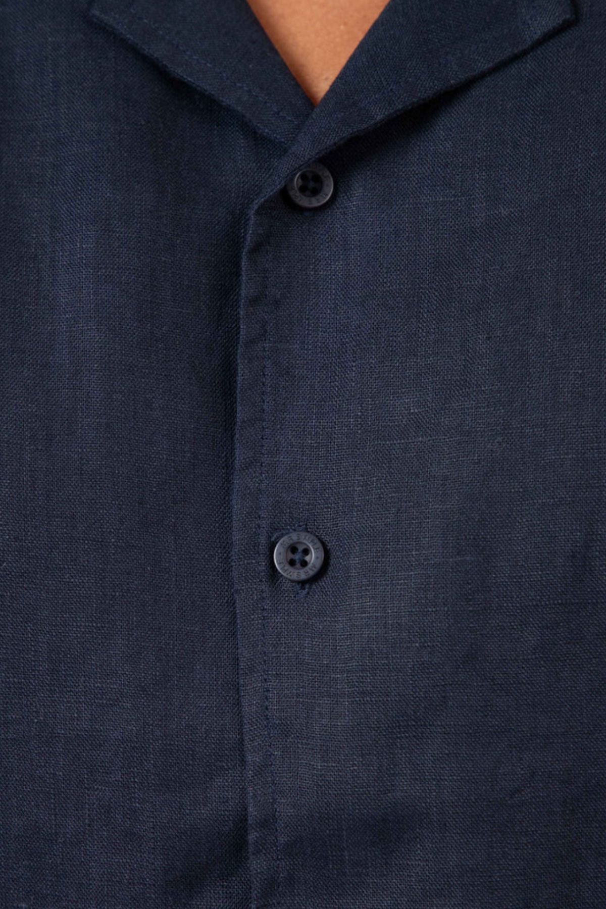 Close-up of the Mr Simple Cuban Short Sleeve Shirt in dark navy blue linen, featuring two visible buttons and part of the collar, showcasing its textured fabric and relaxed fit.