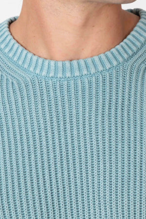 Close-up of a person wearing the Mr Simple Fisher Knit in light blue; features a ribbed texture and relaxed fit with only the lower face and neck visible.