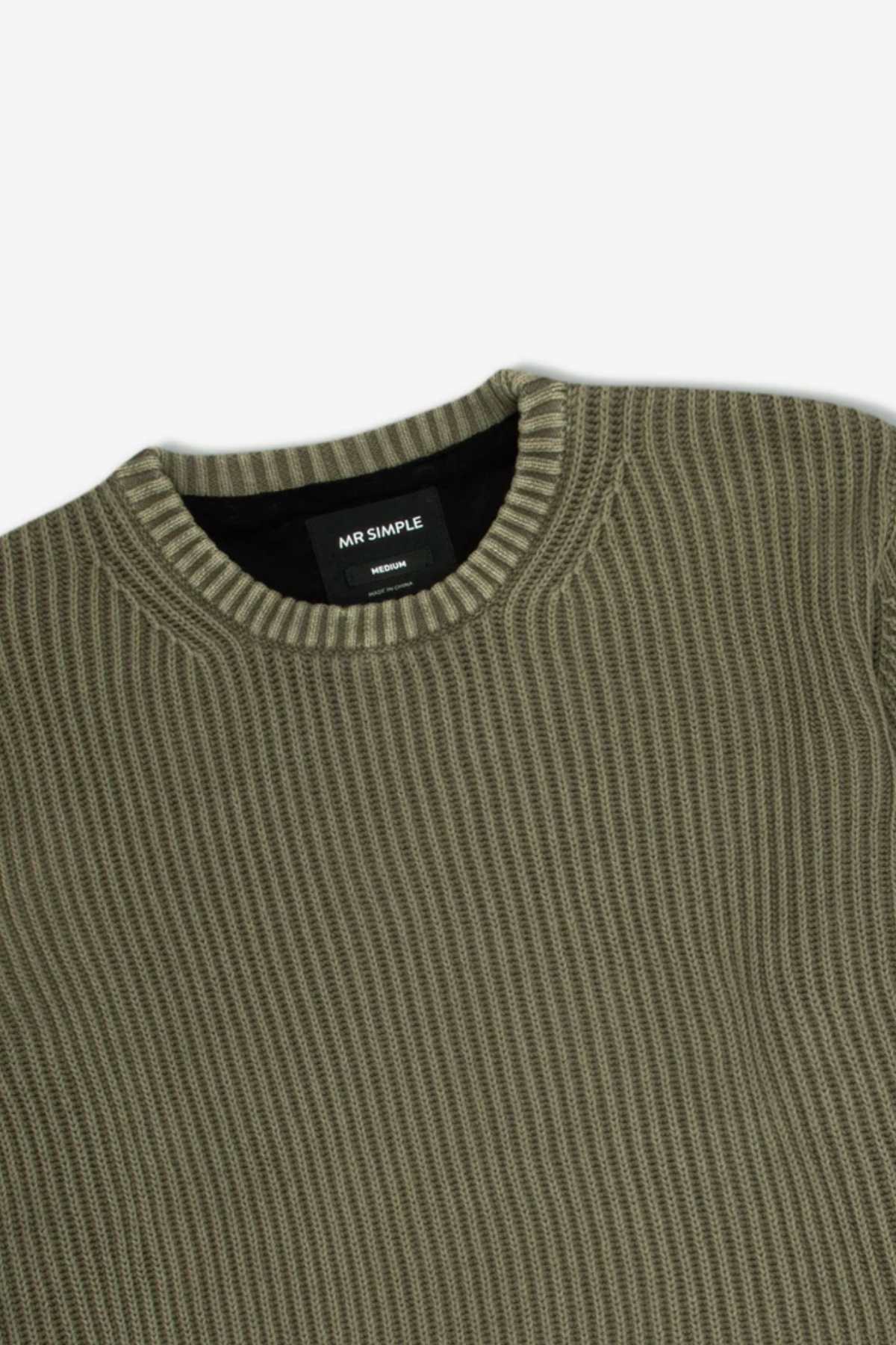 An olive green, ribbed knit sweater with a round neckline is shown. The label inside the collar reads "MR SIMPLE" and "Organic Cotton." This Mr Simple Fisher Knit, featuring a relaxed fit and simple textured design, offers a clean, casual appearance ideal for any laid-back occasion.