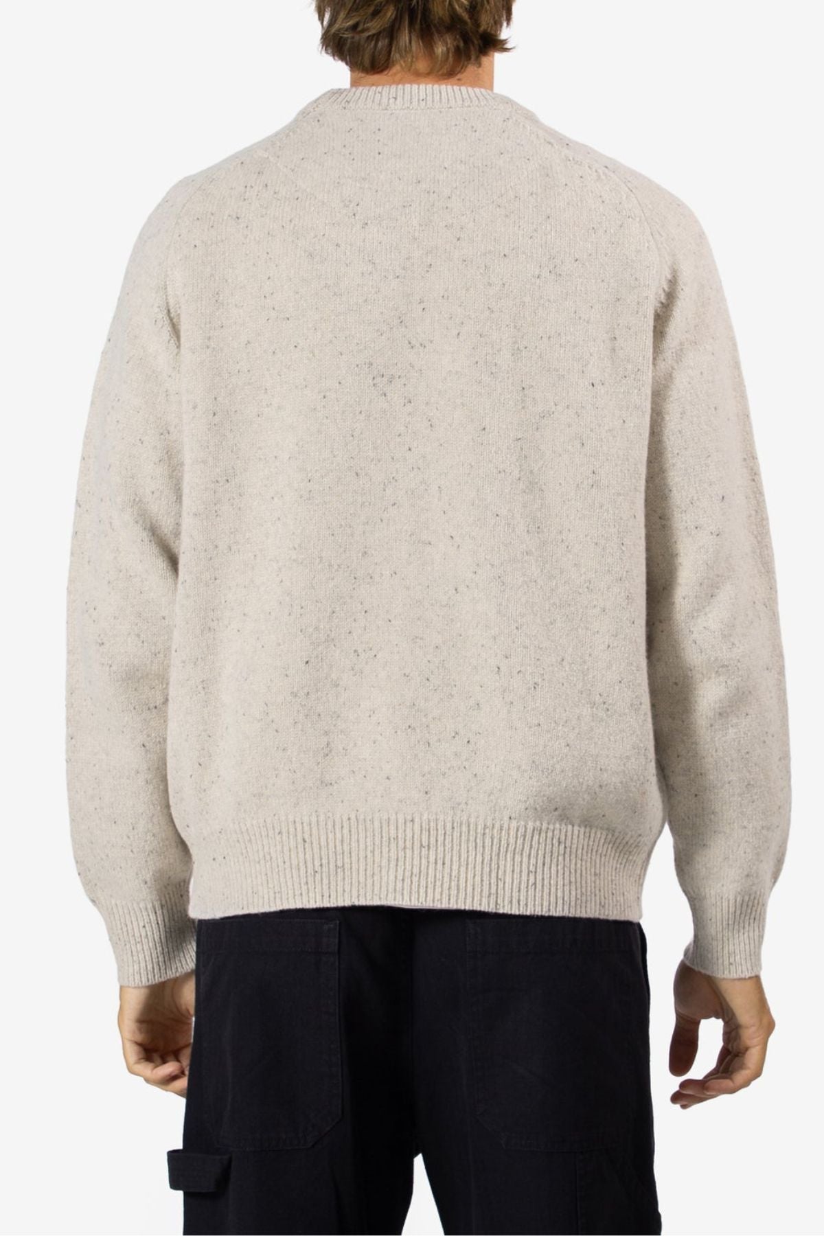 A person stands with their back to the camera, wearing the Mr Simple Fred Knit jumper—crafted from 100% wool—and black pants, showcasing a timeless winter look against a plain white background.