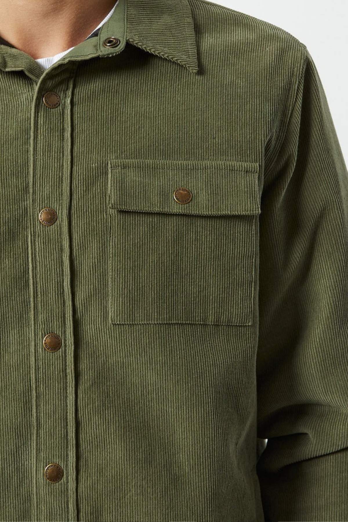 A close-up shows a person wearing the Mr Simple Quilted Cord Jacket in olive green, featuring a button-up front, chest pocket, and quilted lining for added warmth and comfort. Only the shoulders to waist are visible.