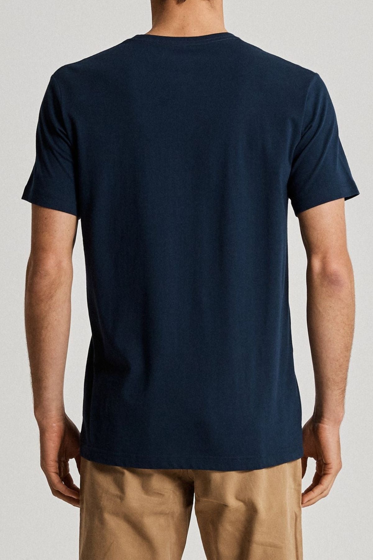 Back view of a person wearing the Reginald Organic Tee by Mr Simple in dark blue and light brown pants against a plain background, highlighting an eco-friendly look.