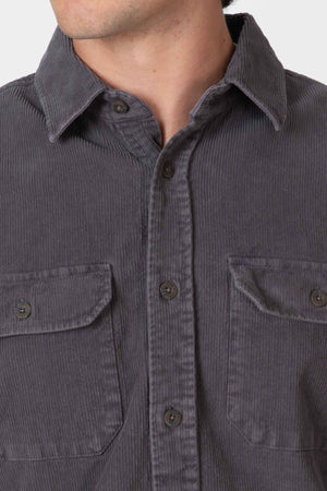 Close-up of a person wearing the Mr Simple Sawyer Cord Shirt in dark gray, featuring two chest pockets, button closures, and a collar. The person's face is partially visible.
