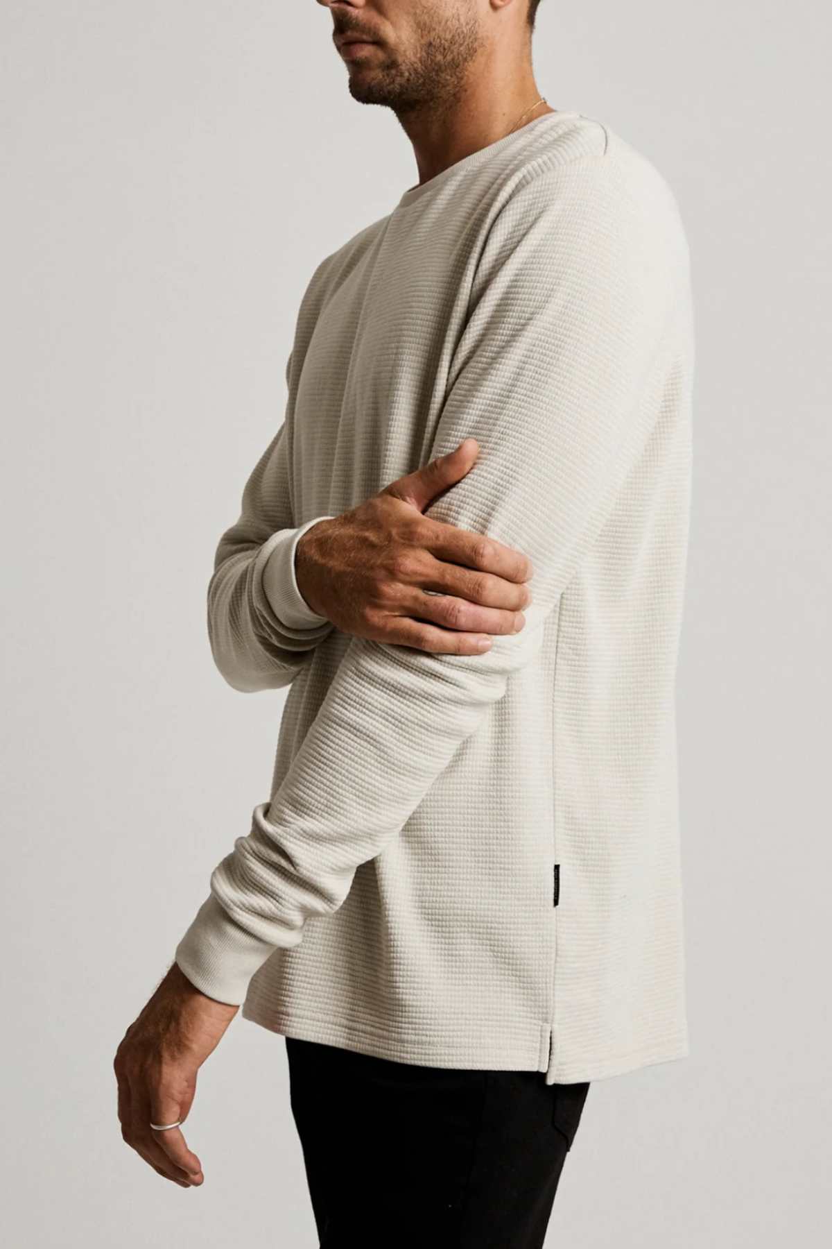Wearing a Mr Simple Smith Waffle classic fit textured shirt in light beige, a person with short hair stands against a plain background, looking left and resting one hand on the opposite elbow.