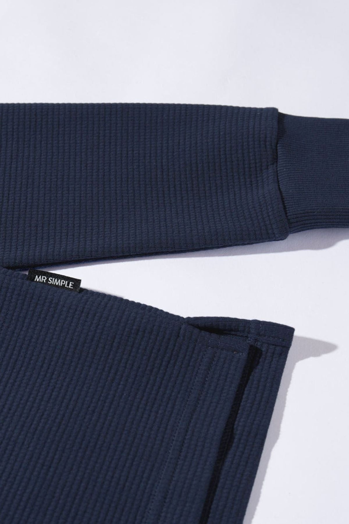 Close-up of the Mr Simple Smith Waffle shirt in navy blue, made from organic cotton with ribbed long sleeves and a visible “MR SIMPLE” tag on the hem, laid flat on a white background.
