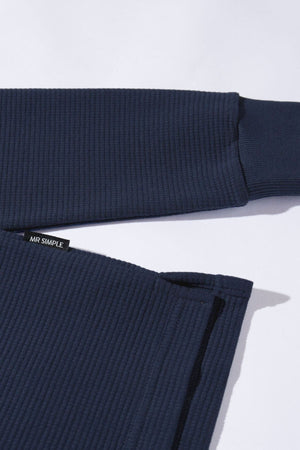 Close-up of the Mr Simple Smith Waffle shirt in navy blue, made from organic cotton with ribbed long sleeves and a visible “MR SIMPLE” tag on the hem, laid flat on a white background.