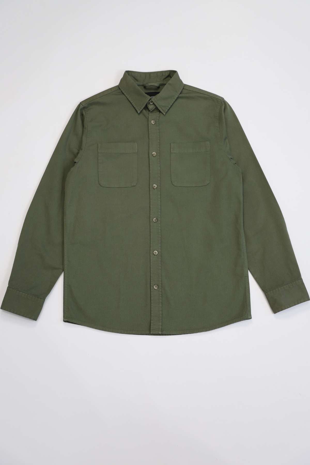 The Mr Simple York Shirt, regular fit, olive green button-up with collar and long sleeves, is set against a light background. Made from 100% cotton, it includes two chest pockets and buttoned cuffs for a casual yet polished look.