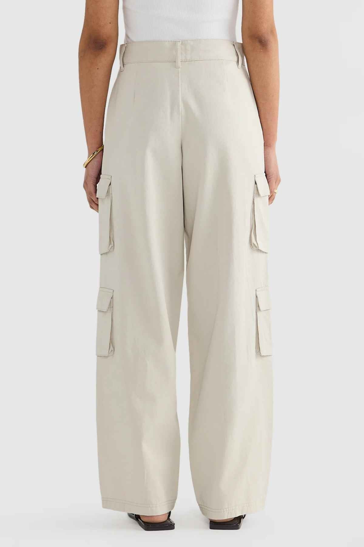 Modeling the ORTC Arden Cargo Pants in cream, which come with practical side cargo pockets, this individual pairs them with a white top and black shoes. Set against a simple white backdrop, they embody both style and comfort thanks to the tencel-cotton material of their outfit.