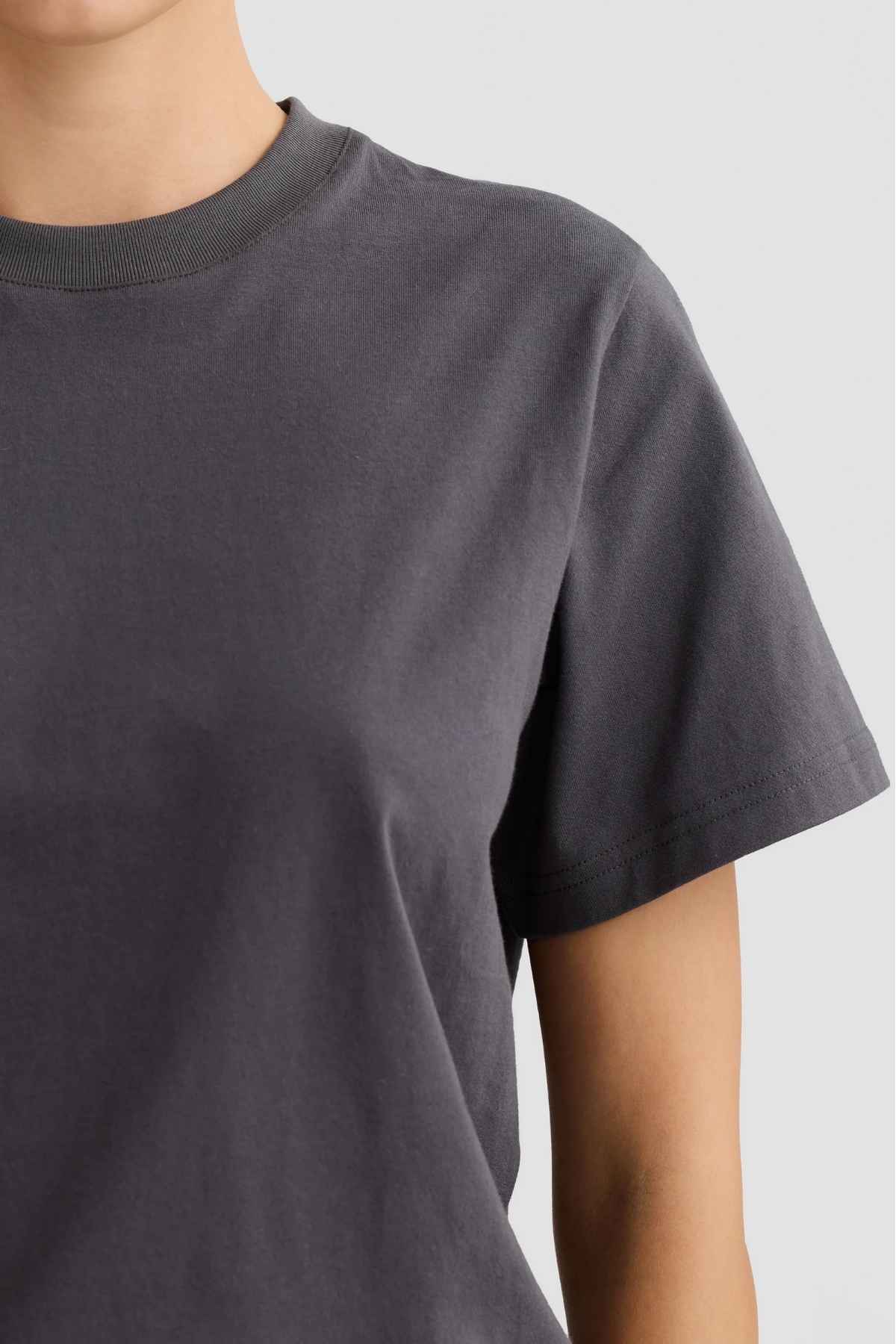Someone is seen wearing the ORTC Everyday T-Shirt, highlighting its relaxed fit and soft, mid-weight cotton, against a neutral background. The image focuses on the upper body and shoulder area, with the head partially cropped from the frame.