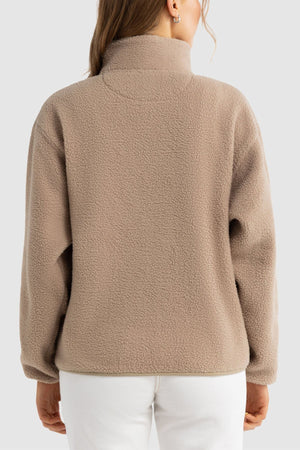 A person with long brown hair, seen from behind, wears the ORTC Sherpa Fleece Quarter Zip in light brown and white pants against a plain light gray background.