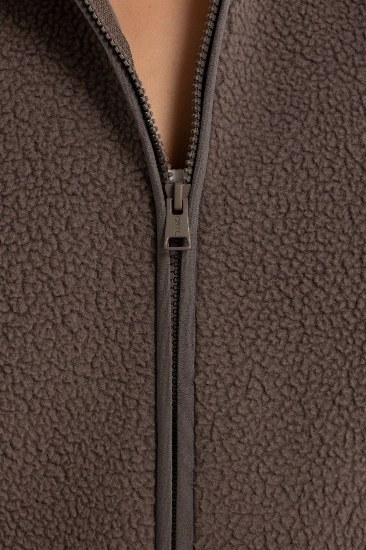 Close-up of the ORTC Sully Sherpa Fleece Vest in brown, featuring textured recycled polyester Sherpa and a partially unzipped front—ideal for cozy layering.