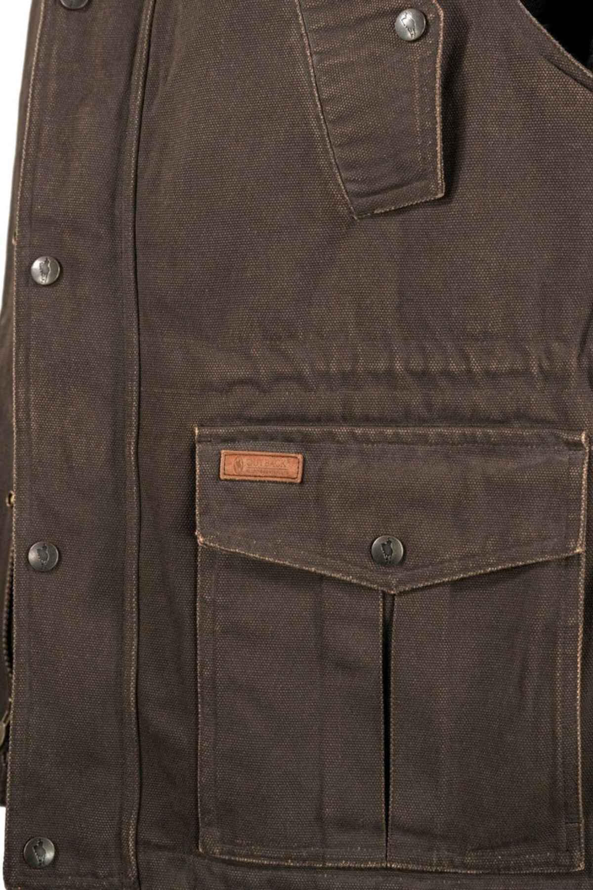 Close-up image of a brown, heavy-duty canvas jacket. The jacket features reinforced stitching, metal snap buttons, and a flap pocket with a small leather tag above it. The material appears rugged and durable, much like the Outback Cattleman Vest, which is designed for outdoor or heavy work use.