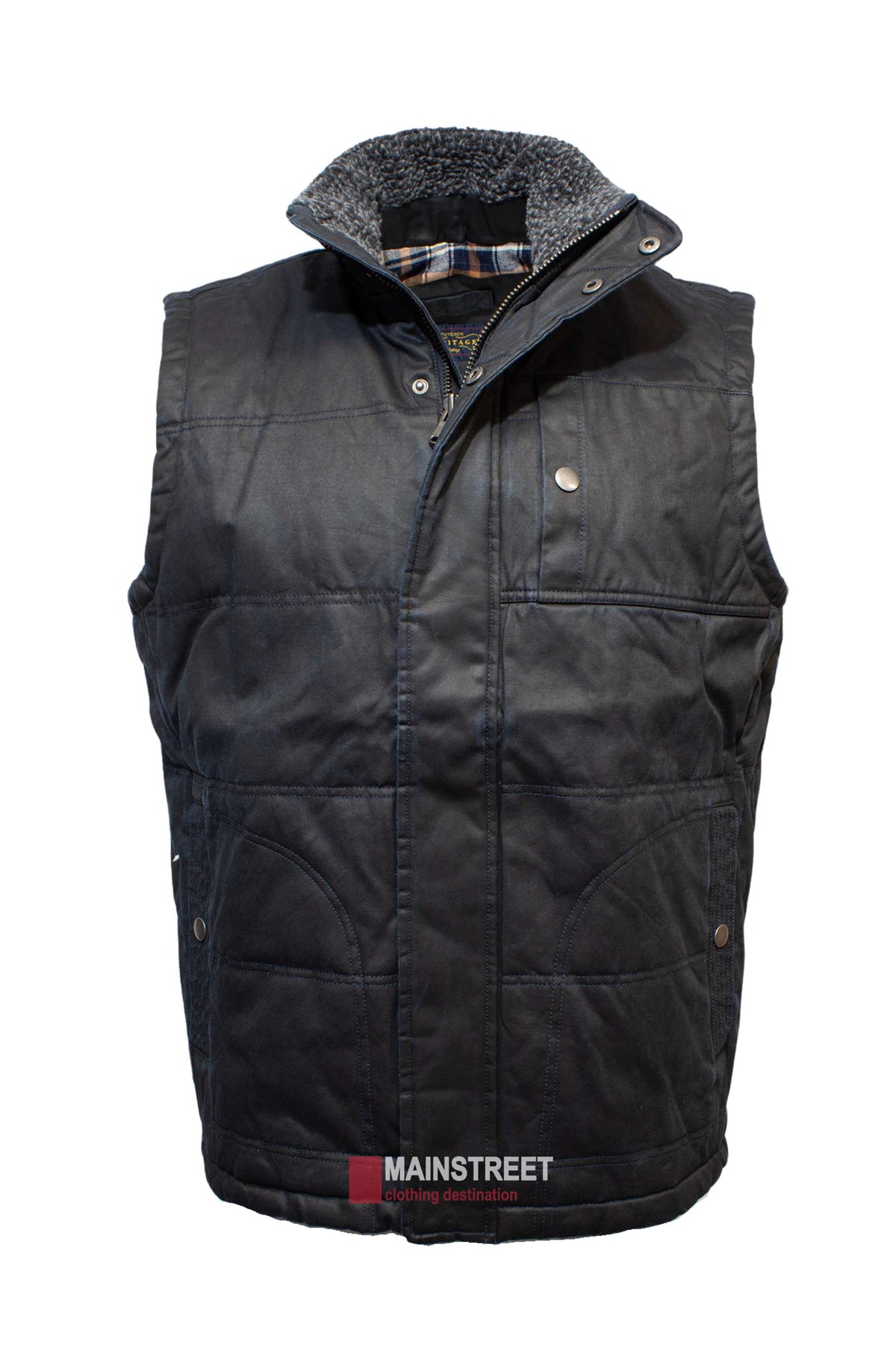 The Outback Heritage Oilskin Vest is a black quilted piece with plaid lining, a sherpa-lined collar, and weather resistance. It includes snap button closures and pockets, with a "Mainstreet Clothing Destination" tag at the bottom.