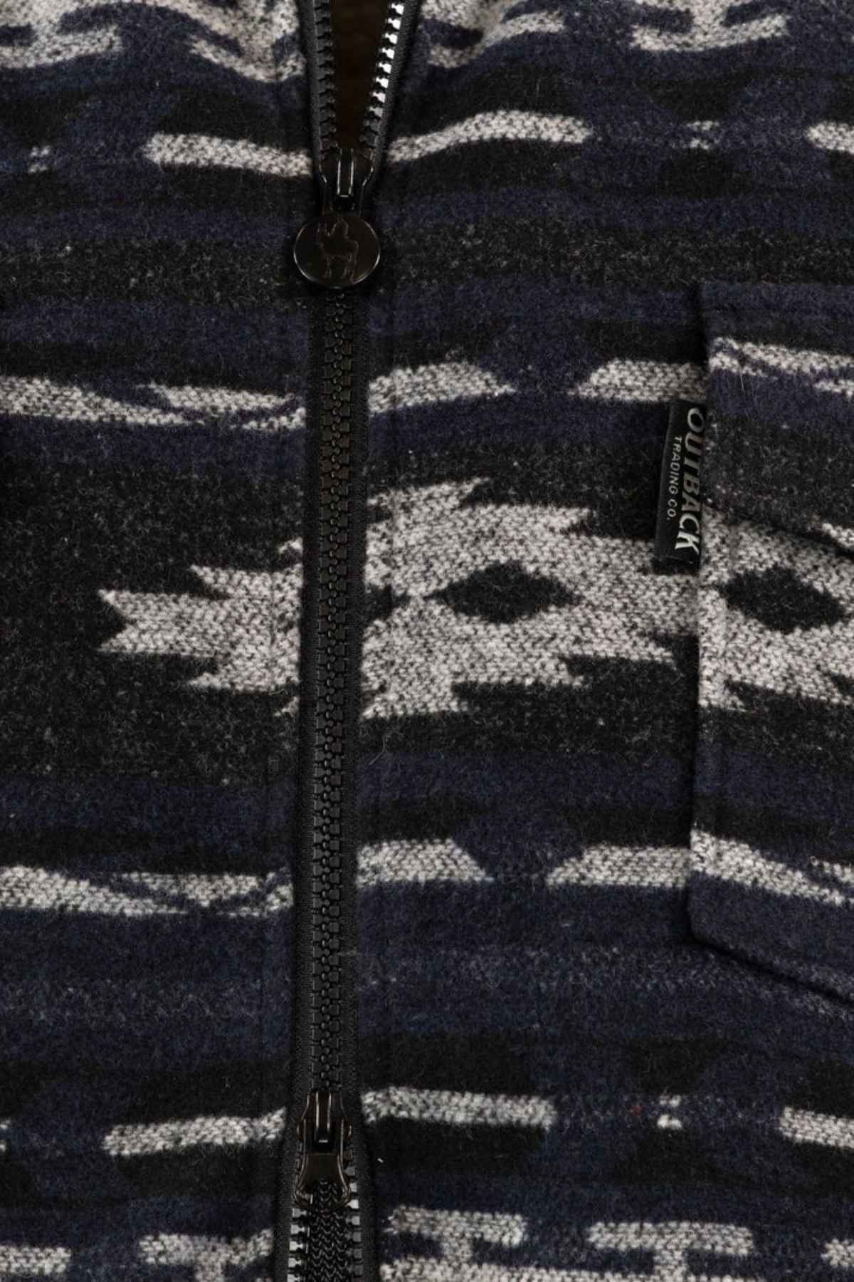 Close-up of the Outback Marc Jacket's dark patterned fabric with a vertical two-way zipper. A small pocket on the right has a black tag labeled "Outback Trading Co." The jacket features a brushed shell, berber lining, and gray-black markings.