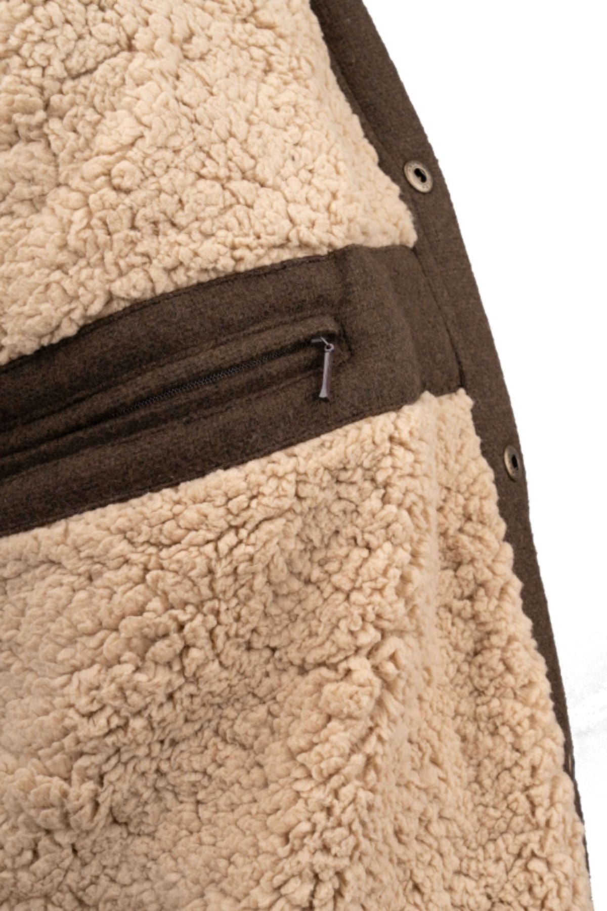 Close-up of the Outback Phoenix Jacket—a beige sherpa jacket featuring a brown zipper pocket and trim, designed for rugged use and inspired by Australian conditions—shown against a white background.