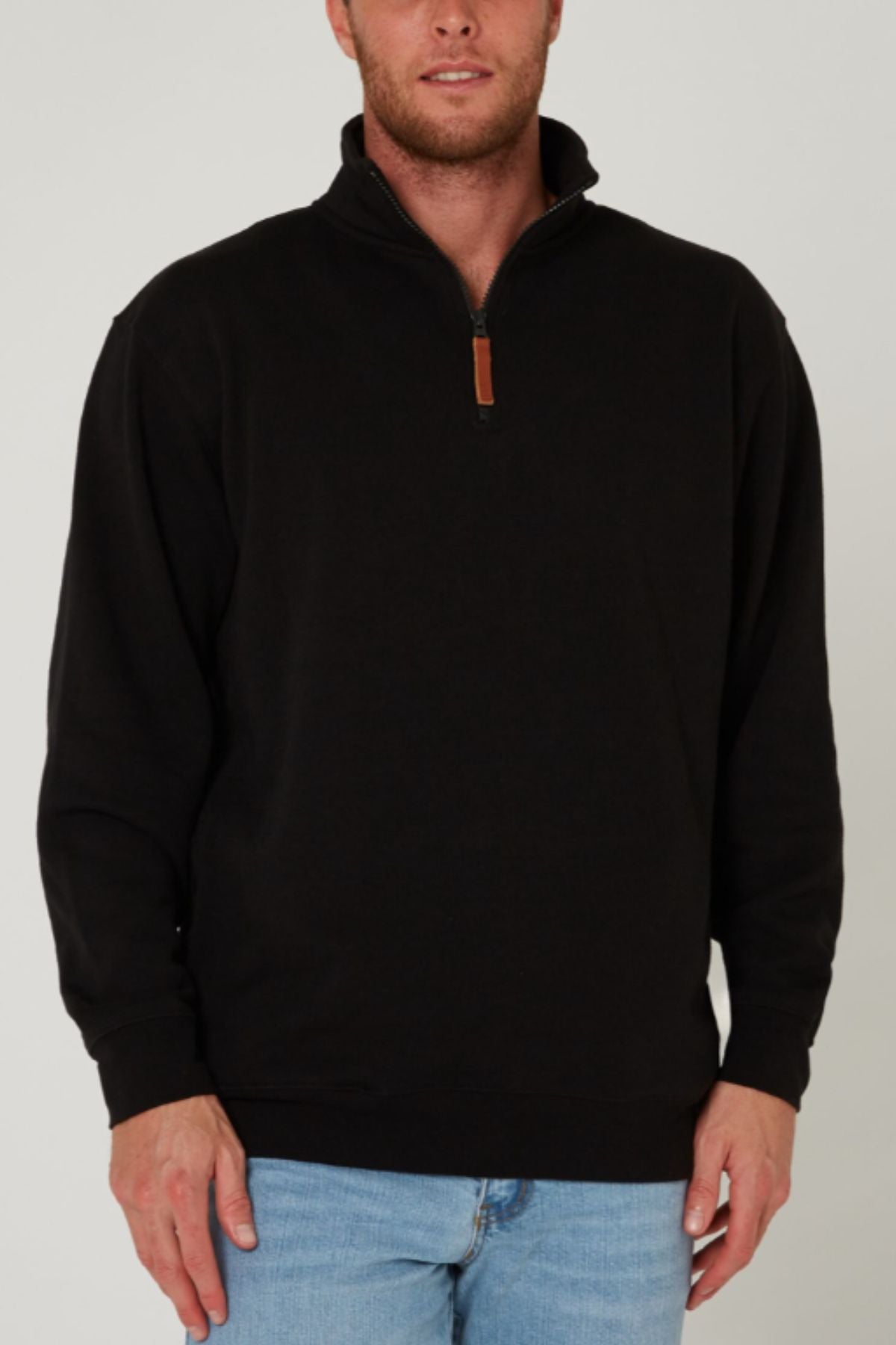 A man wearing a black Pilbara Classic Fleece Pullover with cozy fleece lining and light blue jeans stands against a plain light background. His face is partially out of frame.