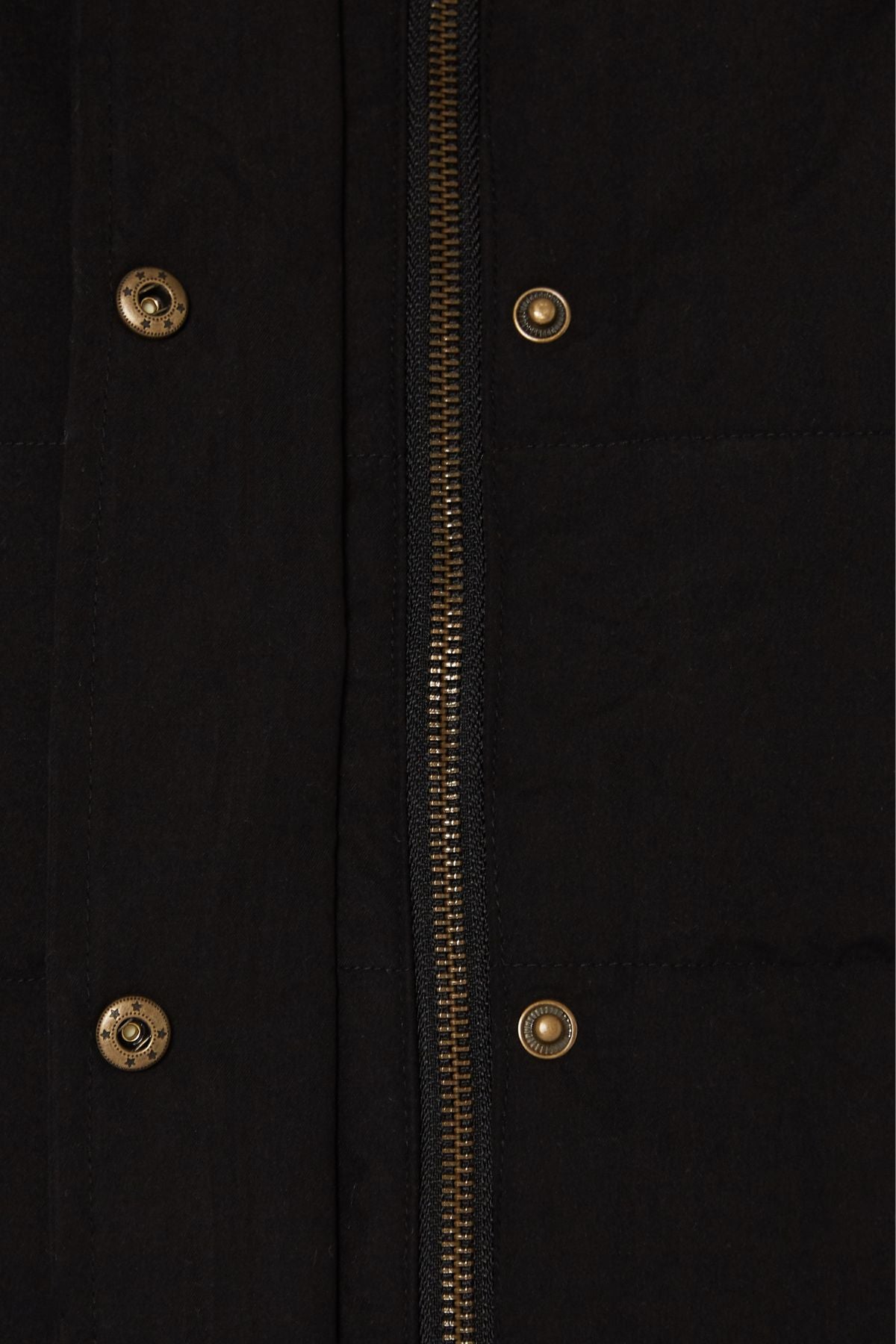 Close-up of the Pilbara Ladies Vest in black microfibre, featuring a vertical metallic zipper, brass snap buttons, and visible stitching and fabric texture.