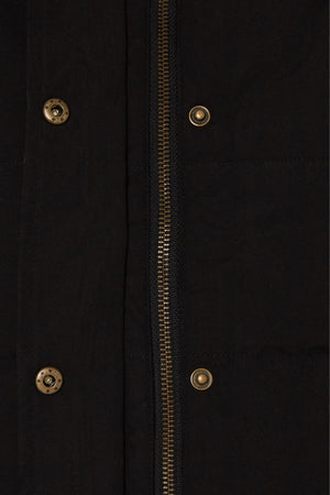Close-up of the Pilbara Ladies Vest in black microfibre, featuring a vertical metallic zipper, brass snap buttons, and visible stitching and fabric texture.