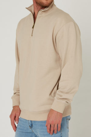 A person in a light beige Pilbara Classic Heavy Weight Fleece Pullover and light blue jeans stands against a plain white background. The cozy fleece adds style and warmth. The person's face is partially out of frame.