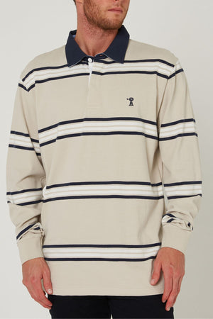 A man wearing the Pilbara Rugby Jersey in beige with navy and white stripes, a dark navy collar, and a small embroidered chest logo stands against a plain background.