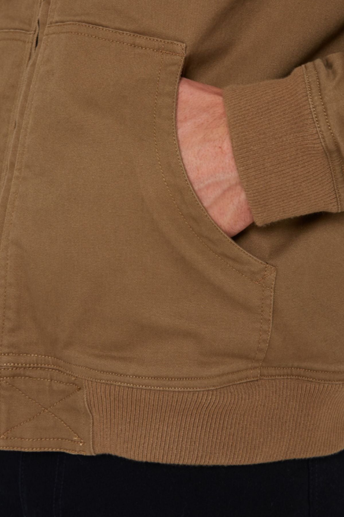 A close-up of a hand tucked into the pocket of a Pilbara Sherpa Bomber Jacket highlights its stitching and ribbed cuff details.