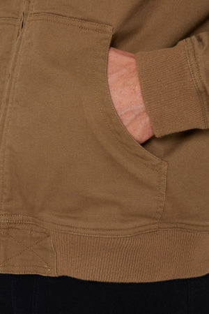 A close-up of a hand tucked into the pocket of a Pilbara Sherpa Bomber Jacket highlights its stitching and ribbed cuff details.