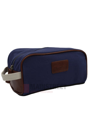 The Pilbara Toiletry Bag is a rectangular navy blue canvas bag with brown leather accents, a beige fabric handle on one end, and a top zipper—ideal for organizing your travel essentials.