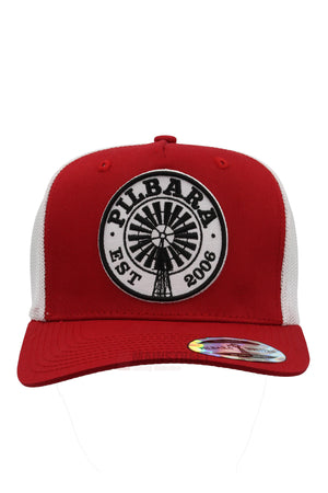 The Pilbara Western Established Cap is red and white with a breathable mesh back, a round black and white "PILBARA EST 2006" windmill patch on the front, and a shiny sticker on the brim.