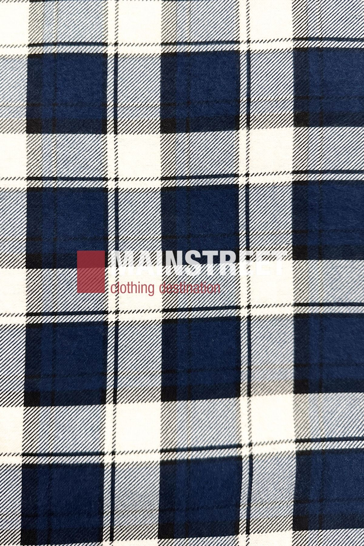 The Pilgrim Closed Front Flannelette Shirt - King Size features a blue, black, and white plaid pattern with long sleeves and a "MAINSTREET Clothing Collection" logo in white and red across the center for classic Pilgrim-inspired style.