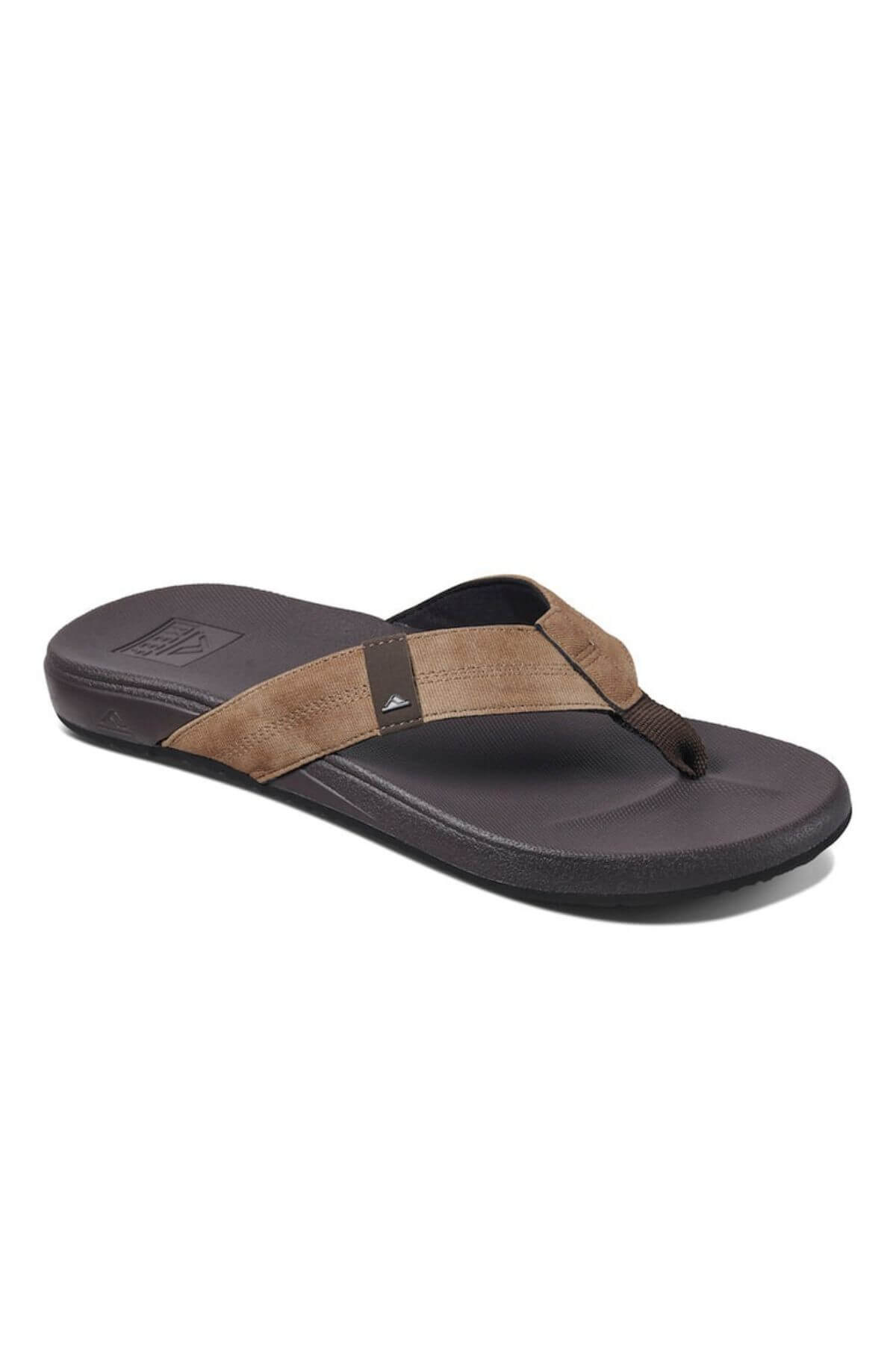 The REEF Cushion Phantom flip-flop, set against a white backdrop, boasts a comfy suede-like brown and black strap adorned with the brand logo. Its durable dark sole enhances the simple yet stylish look, ensuring comfort with every step.