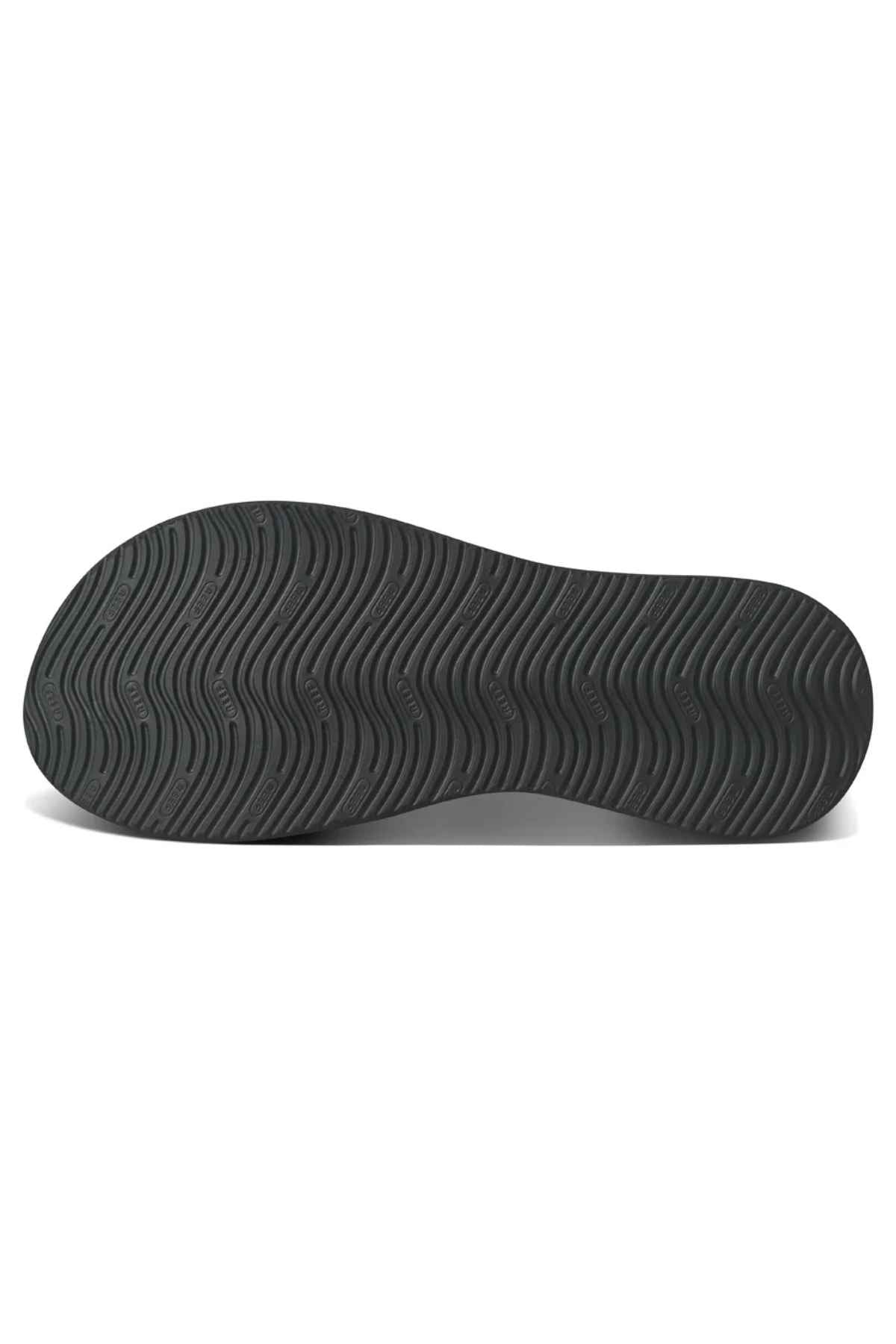 The image shows the black rubber outsole of a REEF Cushion Phantom 2.0 shoe, featuring a wavy, non-slip tread pattern for reliable grip and arch support, ideal for all-day comfort.