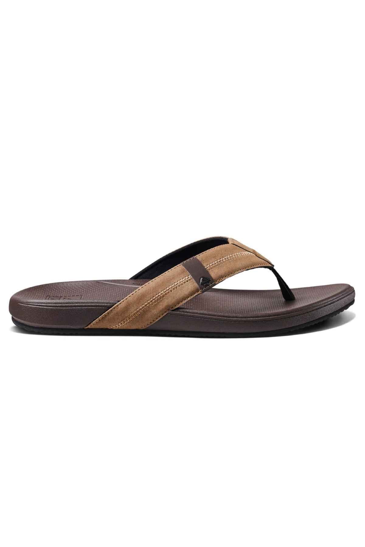 The REEF Cushion Phantom 2.0 is a brown and black flip-flop sandal with a textured footbed, arch support, and a simple thong strap design, shown on a white background.
