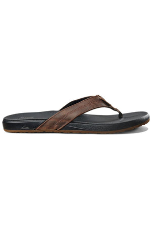 The REEF Cushion Phantom LE is a brown leather strap thong sandal with a black textured sole and cushioned footbed, displayed in side profile on a white background.